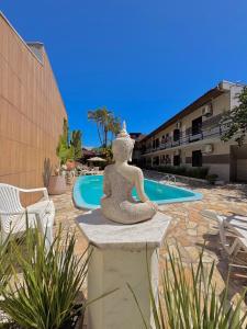 a statue of a woman sitting on a bench near a pool at Pousada Volare in Matinhos