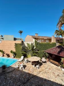 a patio with a pool and chairs and an umbrella at Pousada Volare in Matinhos +36 photos