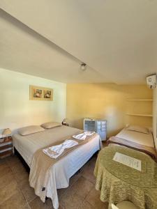 a hotel room with two beds and a tv at Pousada Volare in Matinhos