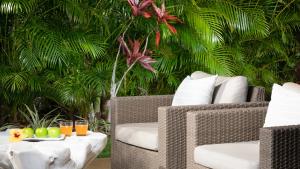 ワイコロアにあるHALE OHONU Stylish 3BR Detached Home Close to KaMilo Poolsの籐の椅子とオレンジとジュースが置かれたテーブル