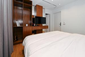 een slaapkamer met een wit bed en een tv bij Wilson On The Bllok in Tirana