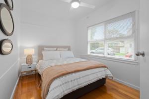 a white bedroom with a bed and a window at Seascape On Cairnes in Indented Head