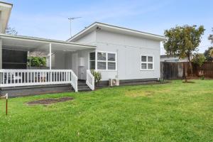 a white house with a porch and a yard at Seascape On Cairnes in Indented Head
