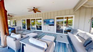 ein Wohnzimmer mit Sofas und einem Deckenventilator in der Unterkunft ALOHA SPIRIT AinaMalu 4BR Home with Outdoor Living Room and Pool in Waikoloa