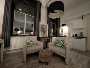 a living room with two chairs and a kitchen at Klooster Mariadal Maastricht in Maastricht