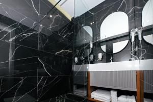 a black bathroom with a sink and a mirror at Wilson On The Bllok in Tirana