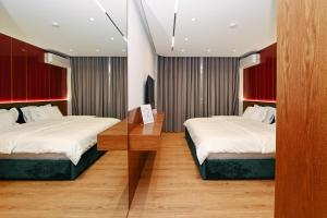 a bedroom with two beds and a wooden table at Wilson On The Bllok in Tirana