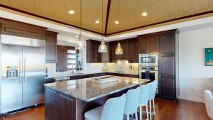 a kitchen with a large island with blue chairs at HAWAIIAN DESTINY Spacious Detached KaMilo 4BR with Heated Pool and Spa in Waikoloa