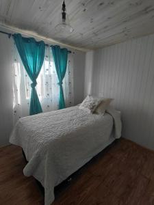 a bedroom with a bed with blue curtains at Cabaña Aeropuerto el Tepual 3 in Puerto Montt