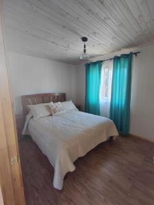 a bedroom with a large bed with blue curtains at Cabaña Aeropuerto el Tepual 3 in Puerto Montt