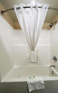a white bath tub with a shower curtain in a bathroom at BCMInns - Peace River in Peace River +31 photos