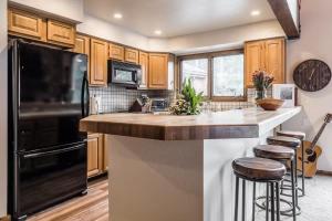 a kitchen with wooden cabinets and a black refrigerator at Spacious 3BD & Loft Villa - Convenient to Slopes in Mammoth Lakes +37 photos