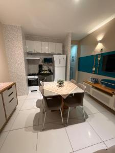 a kitchen with a table and chairs and a white refrigerator at Hospedagem em frente a praia in Salinópolis