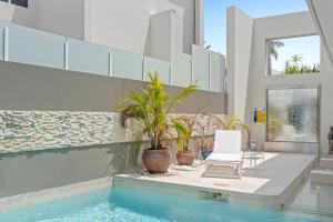 una casa con una piscina con 2 sillas y plantas en 3BR Riverfront Retreat with Office, Pool & Pontoon, en Gold Coast