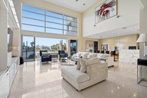 Una sala de estar con muebles blancos y una gran ventana. en 3BR Riverfront Retreat with Office, Pool & Pontoon, en Gold Coast