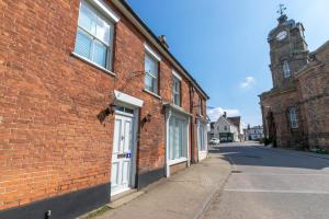 4 Lambseth Street في Eye: مبنى من الطوب وباب ابيض وبرج ساعه