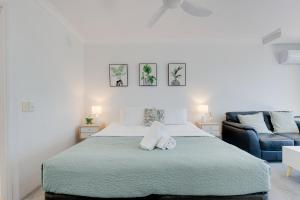 Un dormitorio blanco con una cama y un sofá azul. en Stylish Studio Escape in the Heart of the GC, en Gold Coast