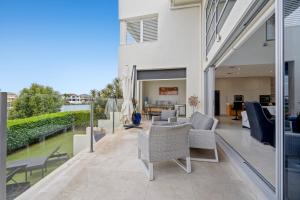 een terras met een tafel en stoelen en een huis bij 3BR Riverfront Retreat with Office, Pool & Pontoon in Gold Coast