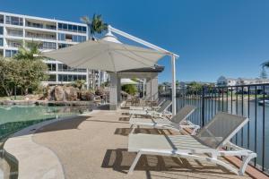 una fila de tumbonas y una sombrilla junto a una piscina en Stylish Studio Escape in the Heart of the GC, en Gold Coast