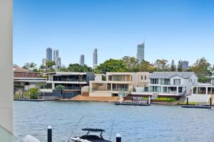 un barco en el agua al lado de algunas casas en 3BR Riverfront Retreat with Office, Pool & Pontoon, en Gold Coast 23 fotos más