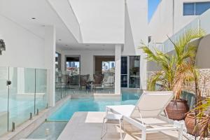 una casa con piscina y 2 sillas blancas en 3BR Riverfront Retreat with Office, Pool & Pontoon, en Gold Coast