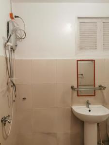 a white bathroom with a sink and a mirror at Latitude 10 Siargao in General Luna
