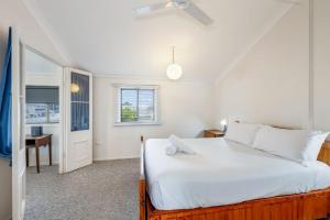 Un dormitorio con una gran cama blanca y un escritorio. en 55 See Street Bargara, en Bargara