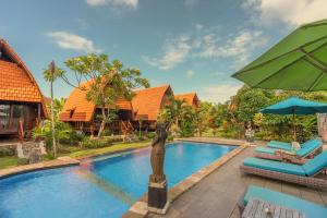 a pool at a resort with a statue in the middle at Harta Lembongan Villas in Nusa Lembongan