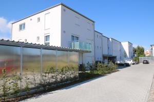 a white building next to a parking lot at Living Neuburg in Neuburg an der Donau