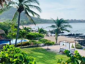 Blick auf einen Strand mit einem Bett und Palmen in der Unterkunft Casa Manzanillo - Jungle Room - Full Ocean View Room at Exceptional Beach Front Location in Troncones