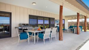 a patio with a table and chairs and a kitchen at ALOHA SHORES Spacious Ainamalu 4BR Home with Mountain and Ocean View in Waikoloa