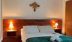 a bedroom with a bed with two lamps and a clock on the wall at Casa Vista Verde in Paraty