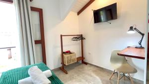 a room with a bed and a desk and a television at Casa Vista Verde in Paraty