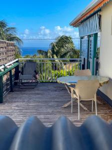 a balcony with a table and chairs and the ocean at Gîte Soleil Canne in Capesterre-de-Marie-Galante