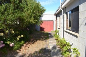an alley next to a building with a red fence at Sound Of The Surf in Evergreen