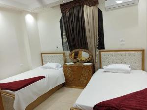 une chambre avec deux lits et un miroir dans l'établissement Elephantine Hotel, à Assouan