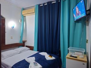 a bedroom with a bed with blue curtains and a tv at Suite aconchegante do Tapana in Belém