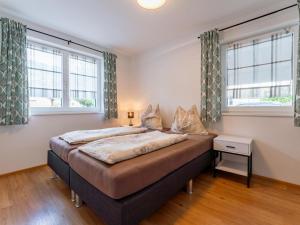 a bedroom with a large bed with two windows at JooP in Niedernsill