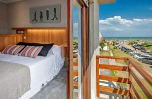 a bedroom with a bed and a balcony with a view at Romina Art Hotel in Villa Gesell
