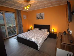 um quarto com uma cama com paredes cor de laranja e uma televisão em Yannsa em Untertweng