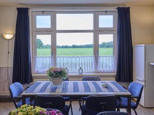 a dining room table with chairs and a large window at Erve Koeleman in Neede