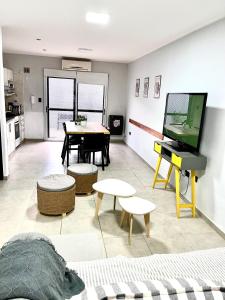 a living room with a flat screen tv and a table at Orillas del Sol Triplex in Chascomús