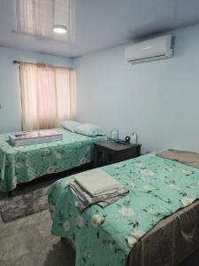a bedroom with two beds and a table and a window at Pequeña Casita Karina in Nicoya