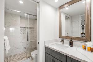 a bathroom with a sink and a toilet and a mirror at Elegant Maui Banyan, Pool, Hot Tub, Across Kamaole II Beach Park in Wailea