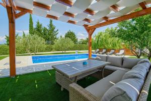 um pátio com um sofá, uma mesa e uma piscina em Family-friendly apartments with swimming pool Ljubac, Zadar - 14148 em Krneša