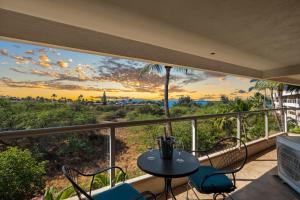 a balcony with a table and chairs and a view of the ocean at Elegant Maui Banyan, Pool, Hot Tub, Across Kamaole II Beach Park in Wailea