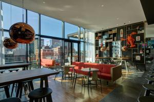 een restaurant met een rode bank en tafels en ramen bij citizenM Boston North Station in Boston +62 foto's