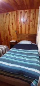 a bed in a room with wooden walls at Cabañas francisca in Valdivia +5 photos