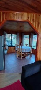 a living room with a table and chairs and windows at Cabañas francisca in Valdivia