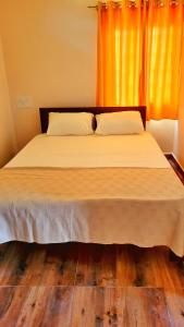 a bedroom with a large bed with an orange curtain at Eden Garden Bandipur Tiger Reserve in Gundlupet